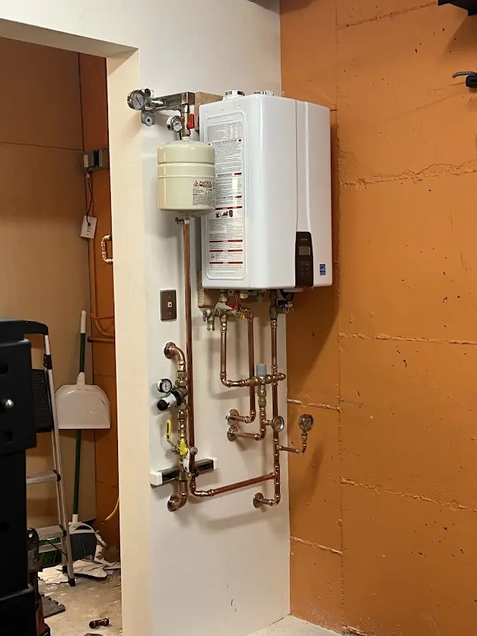 Plumbing technician inspecting water heater connections in Utica